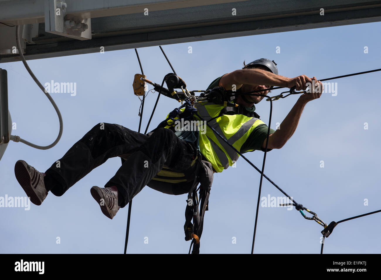 Tradesman workman cleaning a roof using ropes and pulleys abseil mountaineering climbing equipment Stock Photo