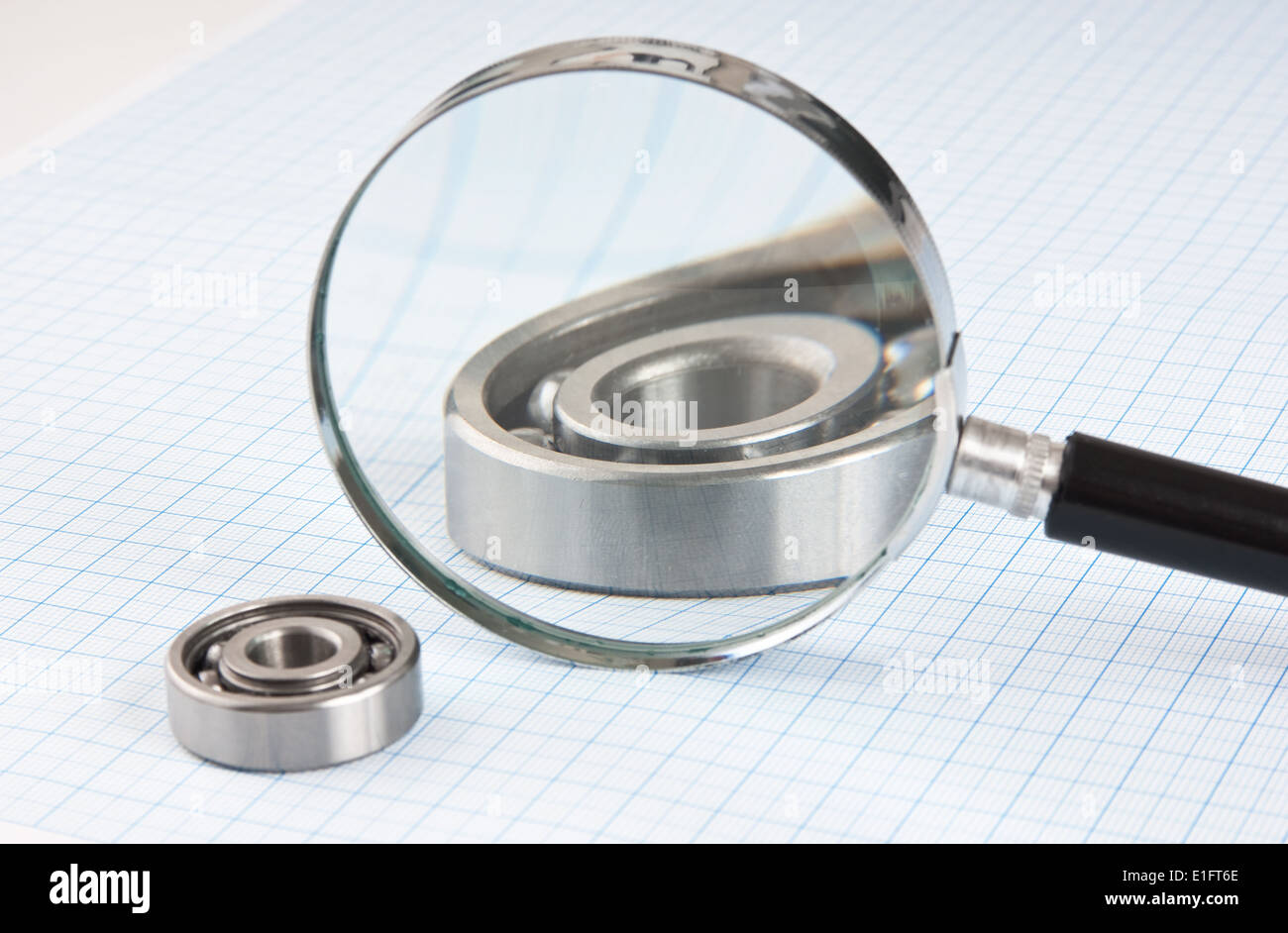 magnifying glass and bearing on graph paper Stock Photo Alamy