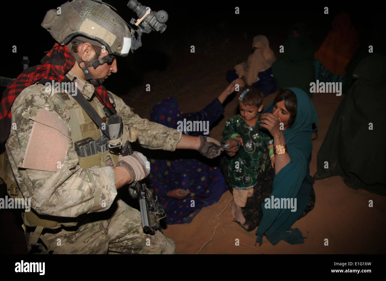 Afghan National Army soldiers give a child candy during a a nighttime search for Taliban insurgents with US Army soldiers August 8, 2013 in Zharay district, Kandahar province, Afghanistan. Stock Photo