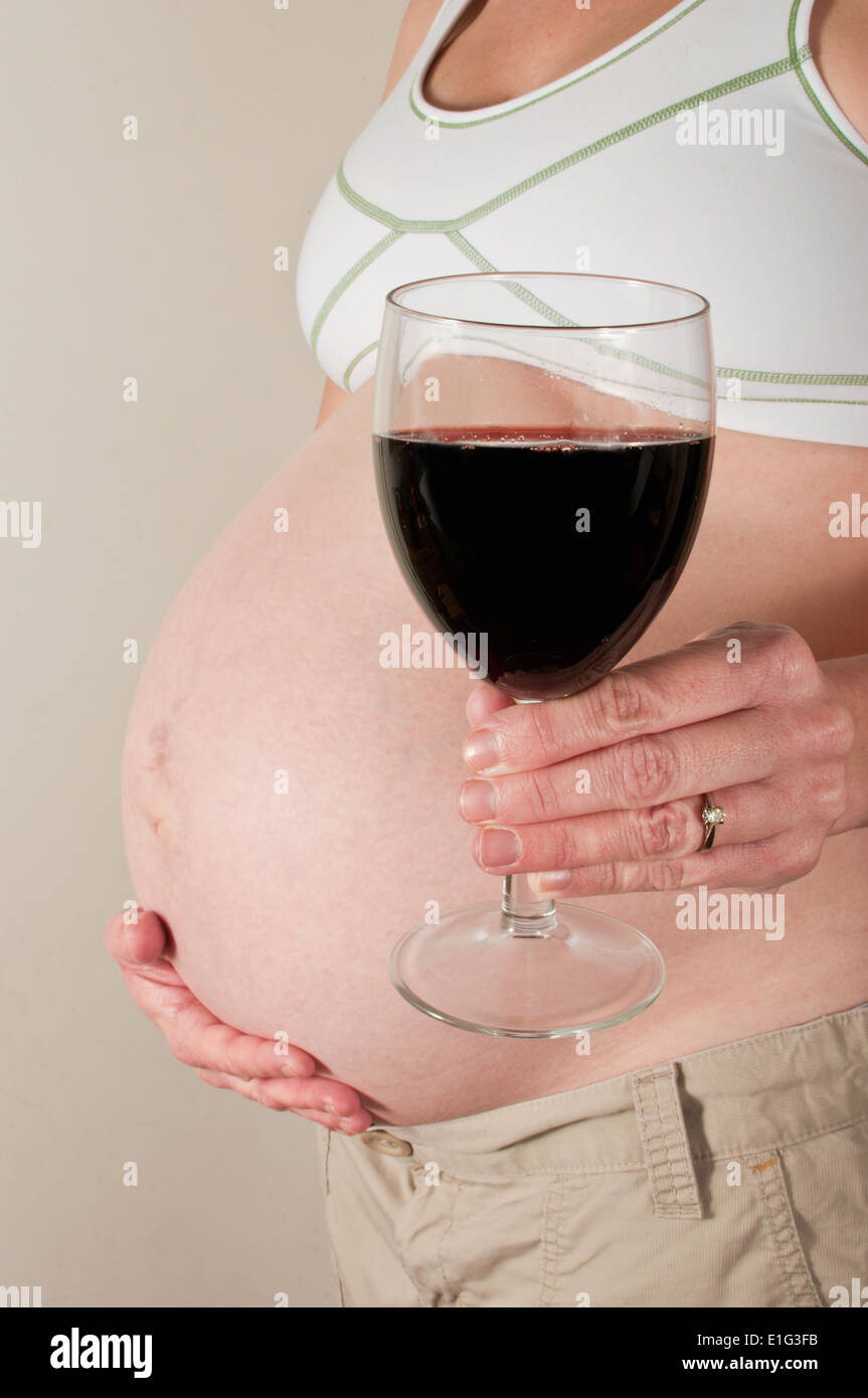 Pregnant woman drinking a glass of red wine Stock Photo