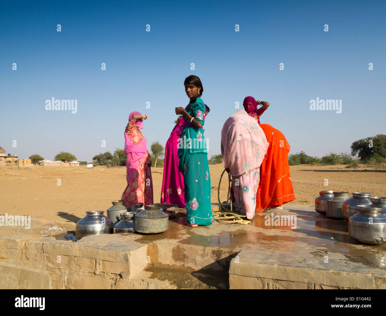 India, Rajasthan, Jaisalmer, Thar Desert, Khuri, colourfully dressed women collecting water from village well Stock Photo