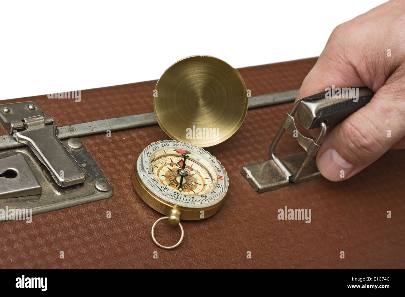 old suitcase in hand and compass isolated on white background Stock Photo