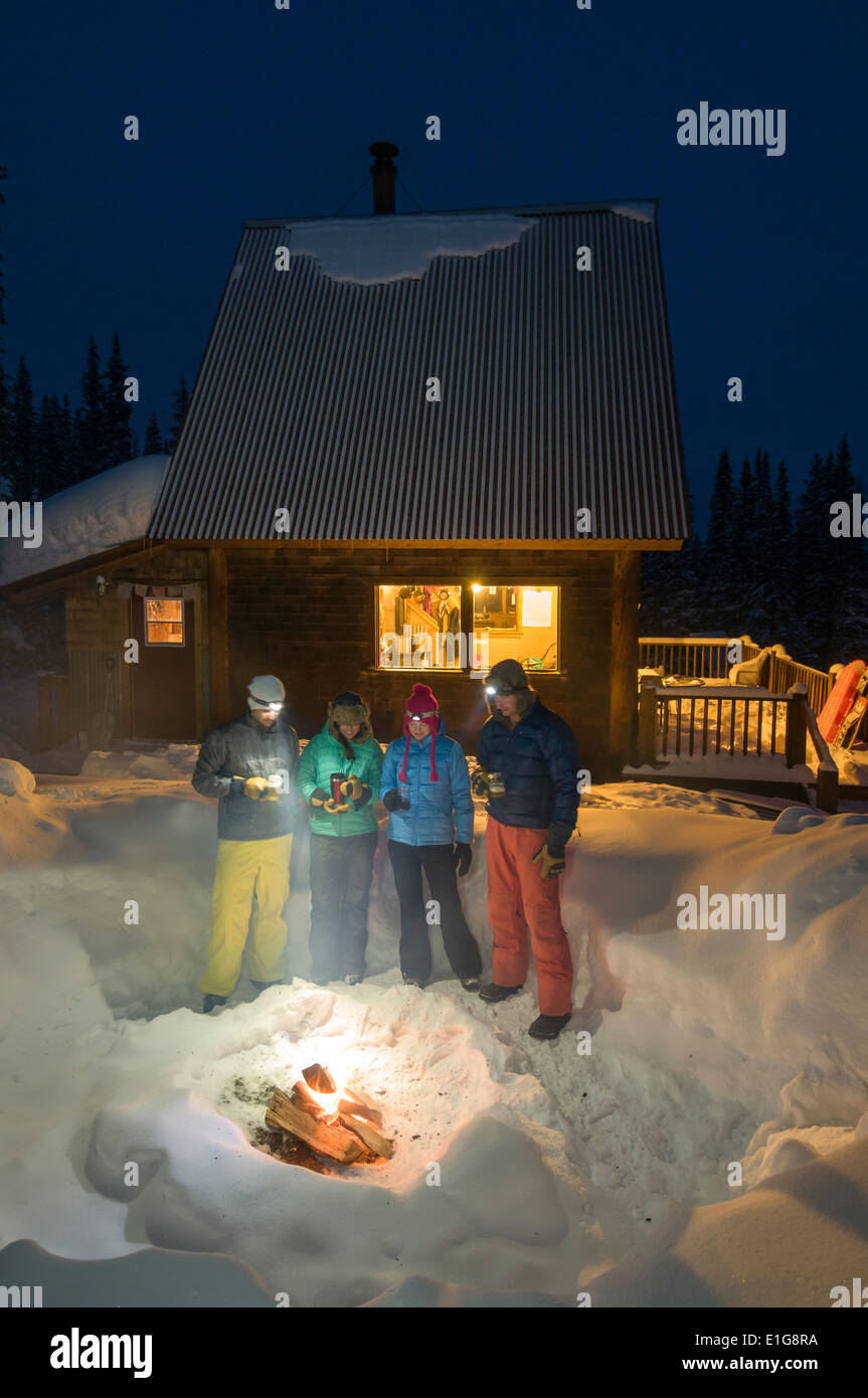 A group of adults enjoying an evening fire outside of a backcountry ski hut near Molas Pass, Silverton, Colorado. Stock Photo