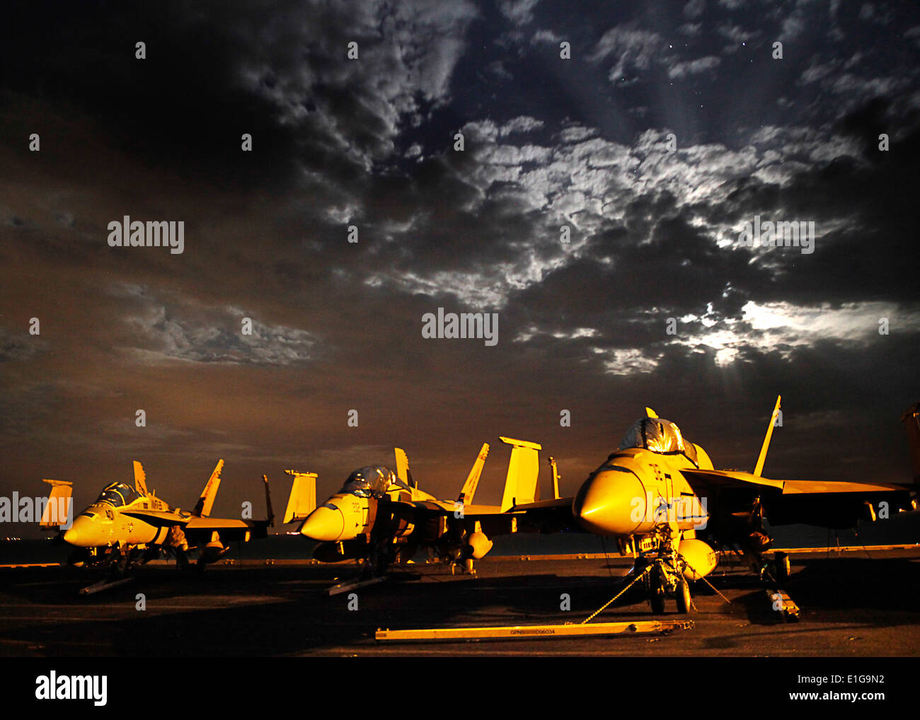 From left, a U.S. Marine Corps F/A-18C Hornet and two Navy F/A-18E-F Super Hornet aircraft are illuminated by lights on board t Stock Photo