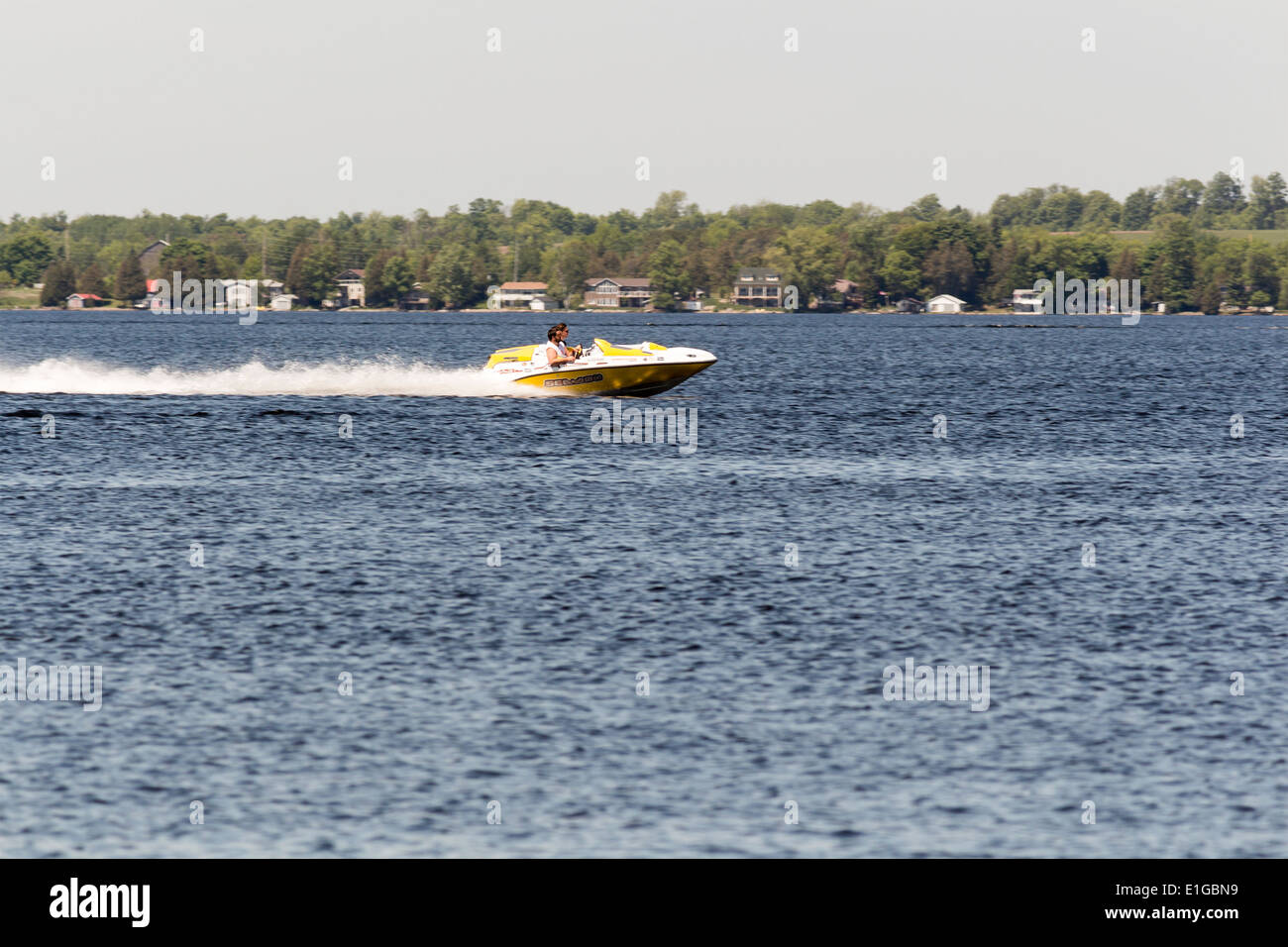 Two people in a Sea Doo speedboat going fast across across Cameron Lake in Fenelon Falls, Kawartha Lakes Ontario Stock Photo