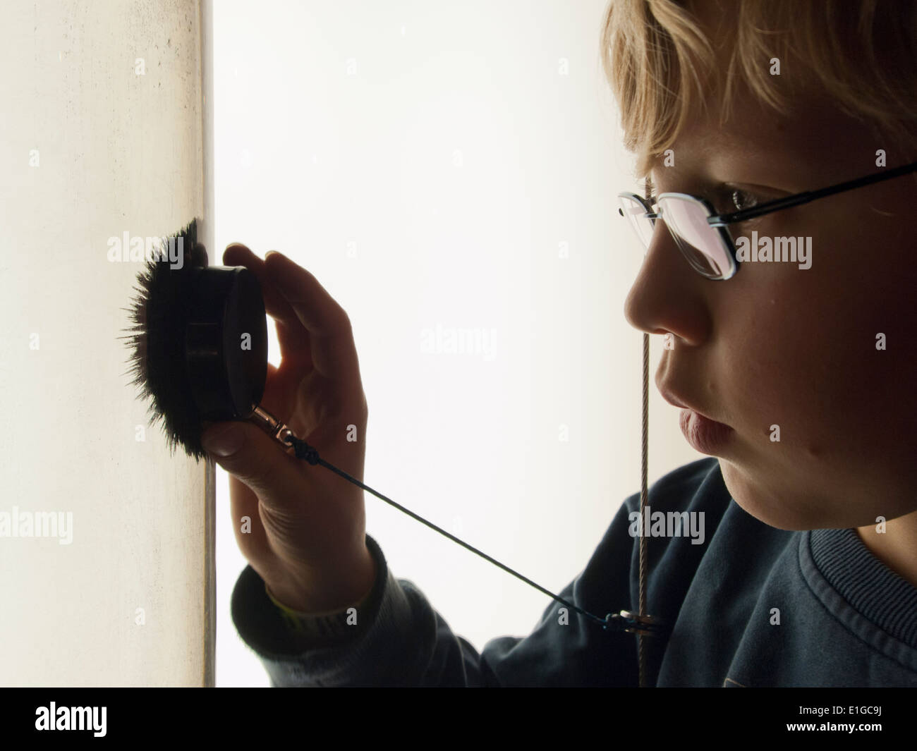 A 12-year old boy is watching iron filings in a water tank that are attracted by a strong magnet held in the boy's hand Stock Photo