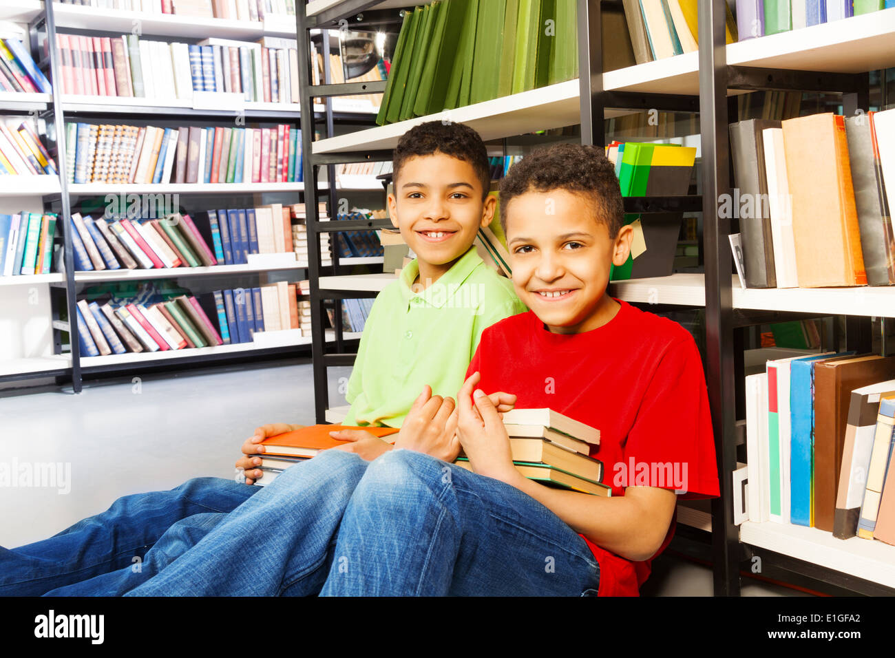 Two happy boys sitting on the floor in library Stock Photo - Alamy