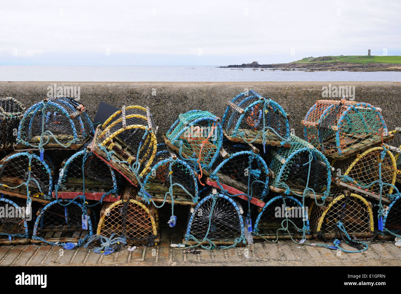 Colourful lobster creels stacked against the harbour wall Stock Photo