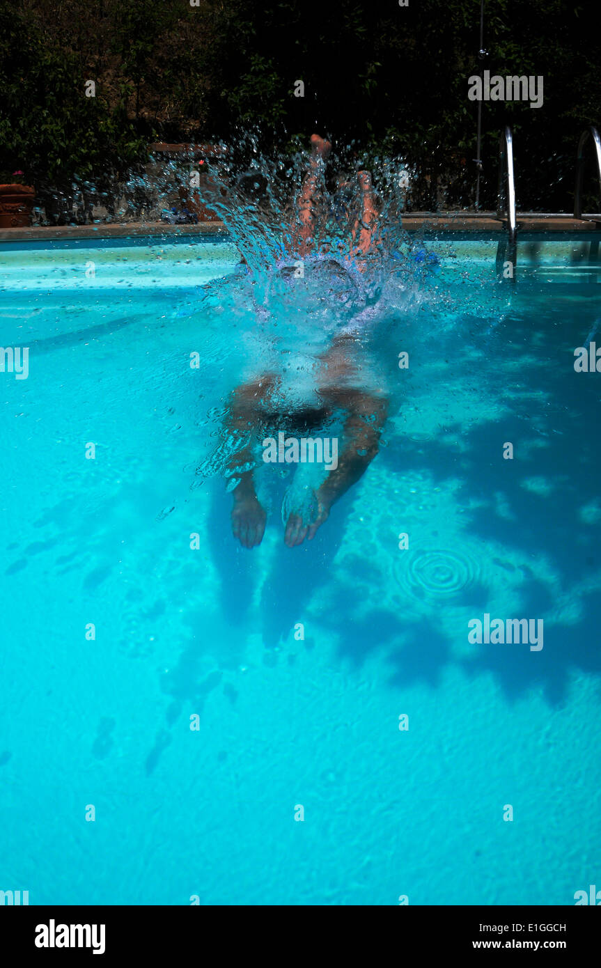 Man diving into swimming pool making a splash Stock Photo