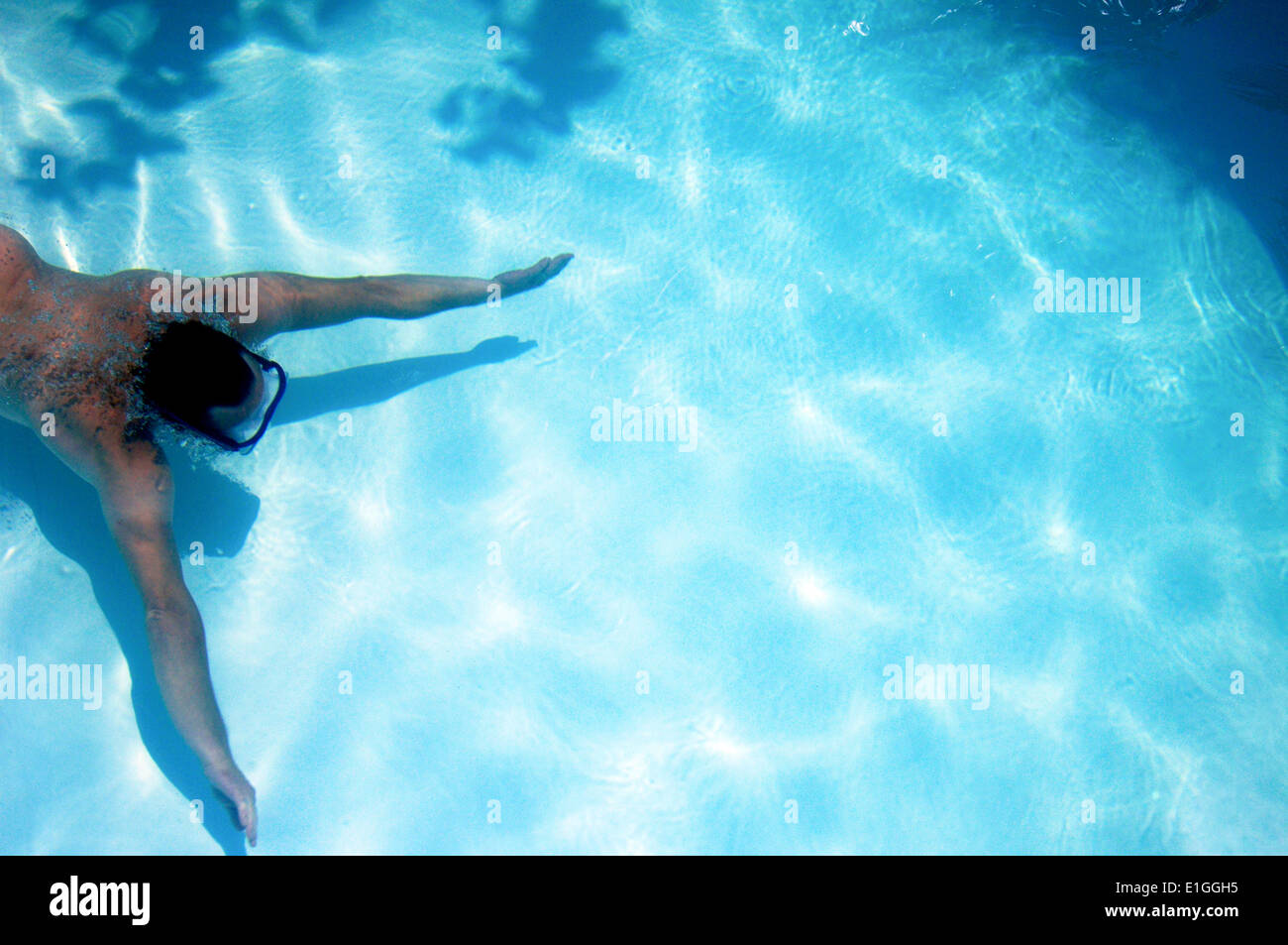 man swimming underwater in a clear blue pool Stock Photo