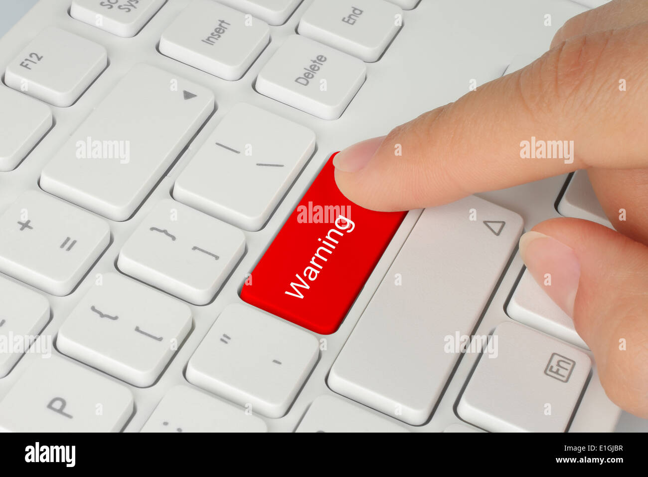 Hand pushing red warning button on the keyboard Stock Photo