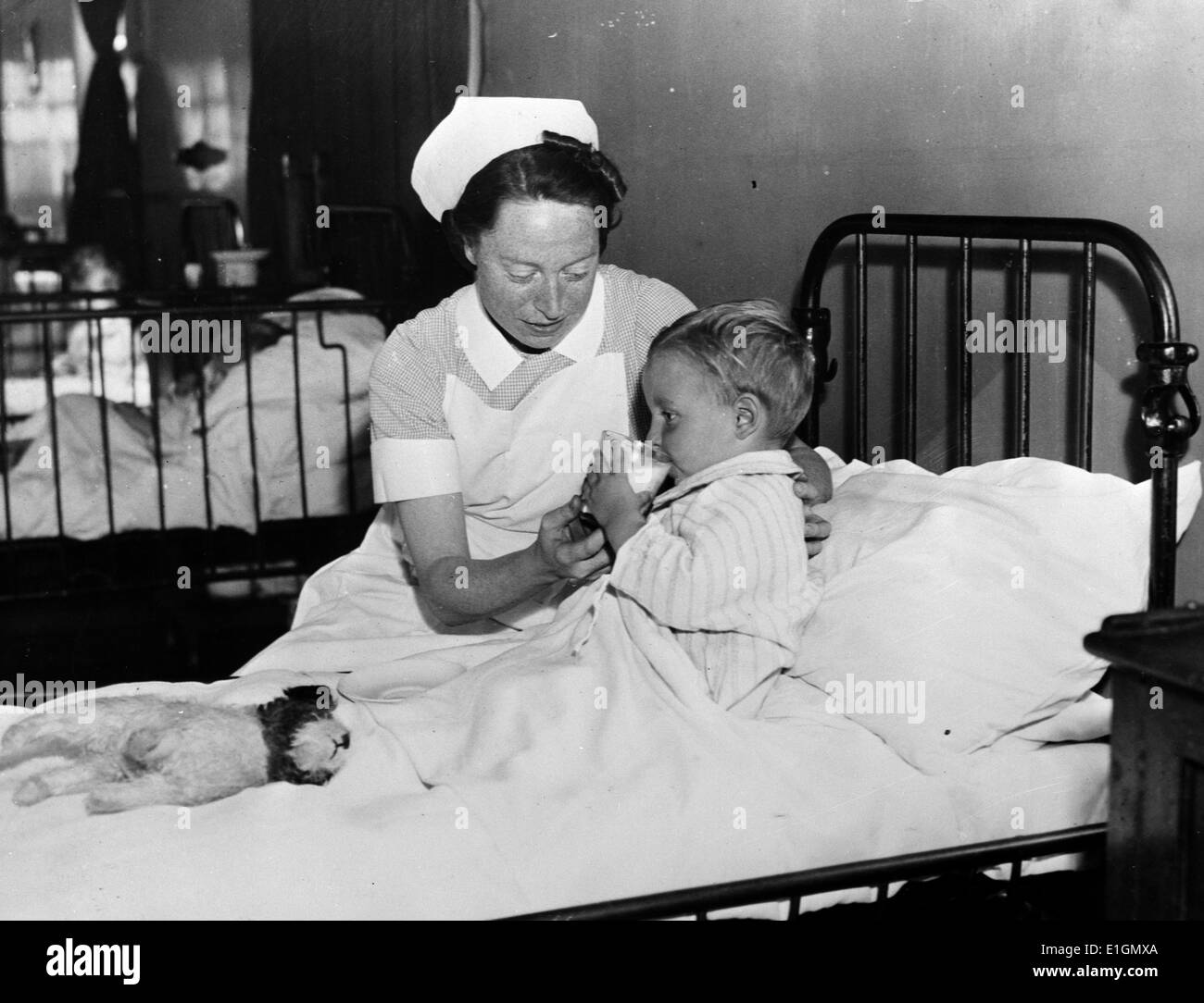 Photograph of a child in a British hospital given a drink of milk. Milk is distributed in Britain after the needs of priority classes. Dated 1938 Stock Photo