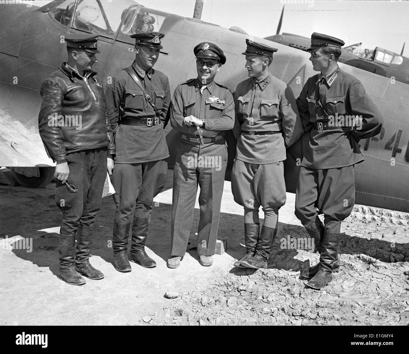 Photograph of Major General Lewis Brererton in the centre, the Commander of the United States Army force in the Middle East with a group of Russian officers standing before an American warplane delivered to the Russians. A United States warplane is being tested in the background and bears the red star insignia of Russia, which is made by filling in the white star of the United States with red paint. Photographed by Nick Parrino. Dated 1943 Stock Photo