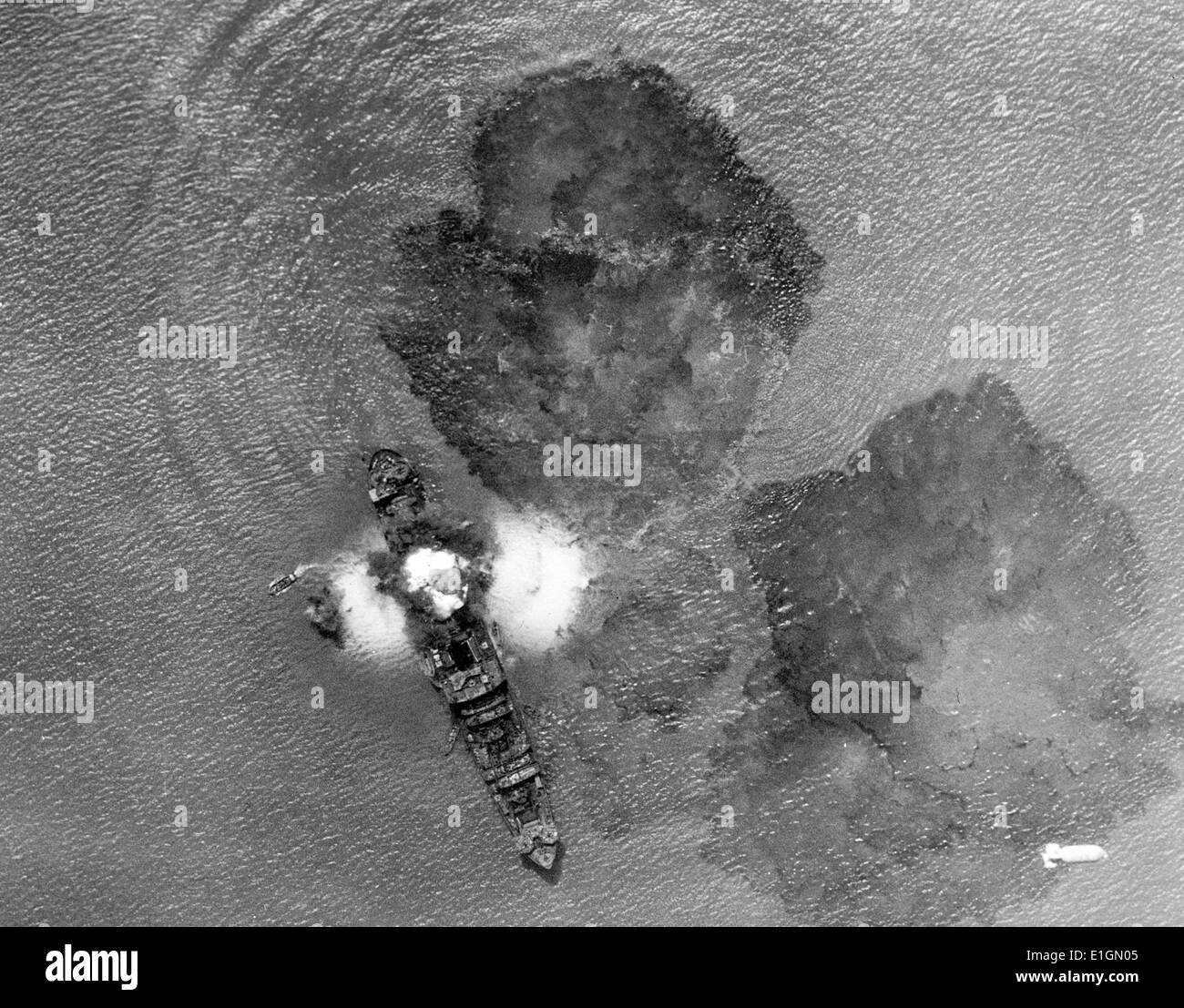 Photograph of a 7,000 ton Japanese merchant vessel after a direct hit by Indian Air Task Forces near Rangoon, India. Small boats filled with crew members can be seen. The waters are covered with oil slick. Dated 1943 Stock Photo