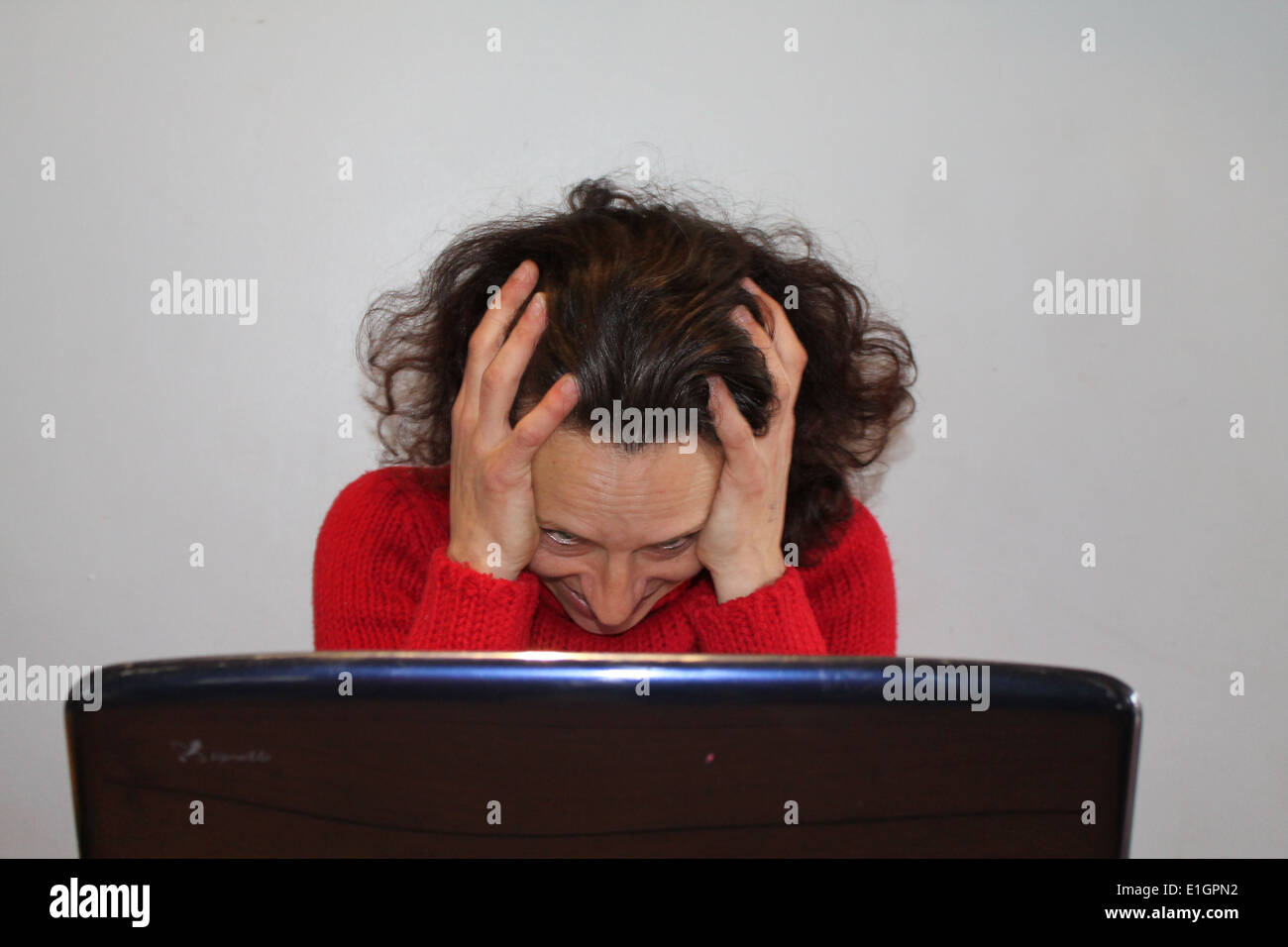A Lady looking Stressed in front of a laptop computer Stock Photo