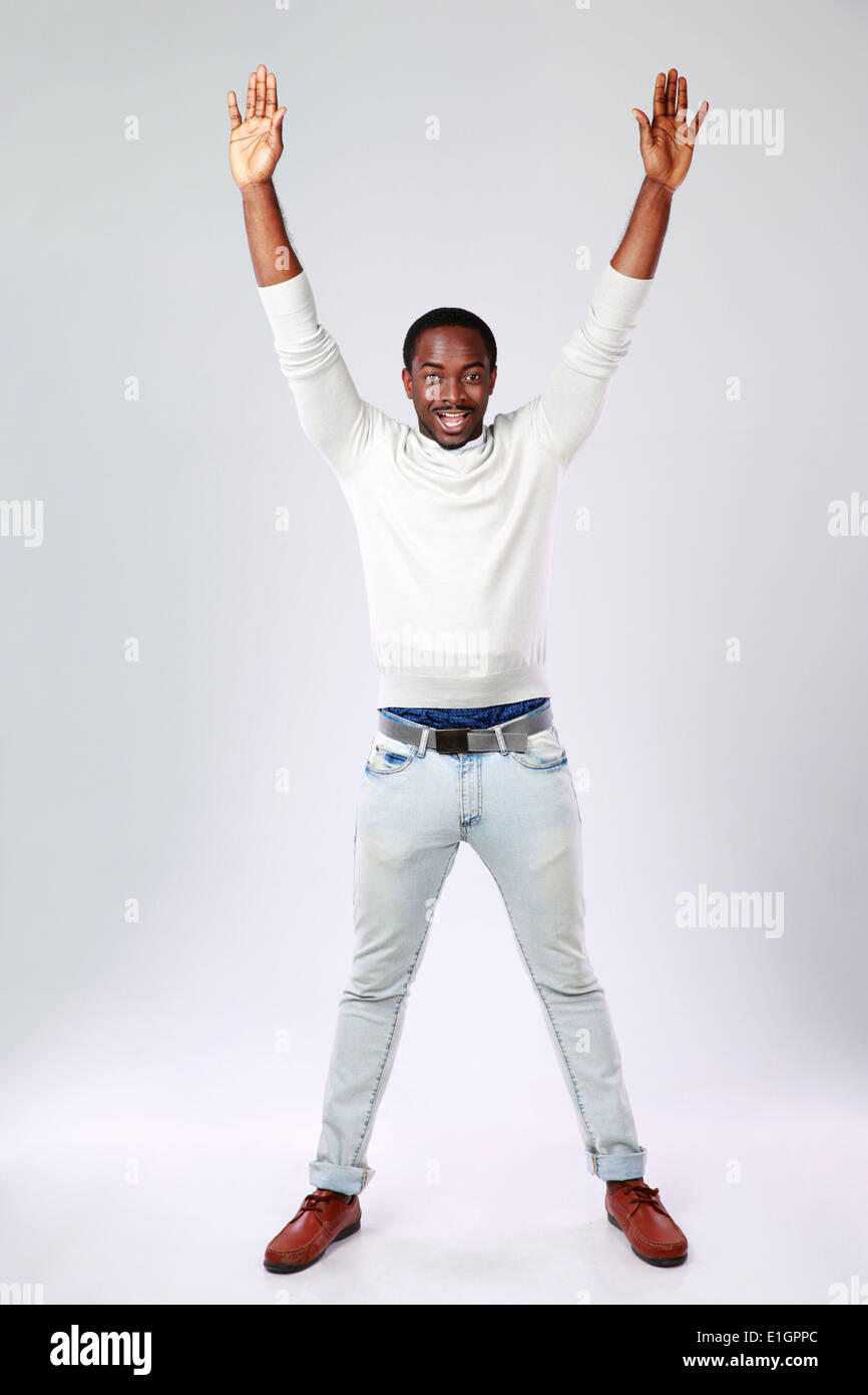 Full length portrait of african man with raised hands on gray ...