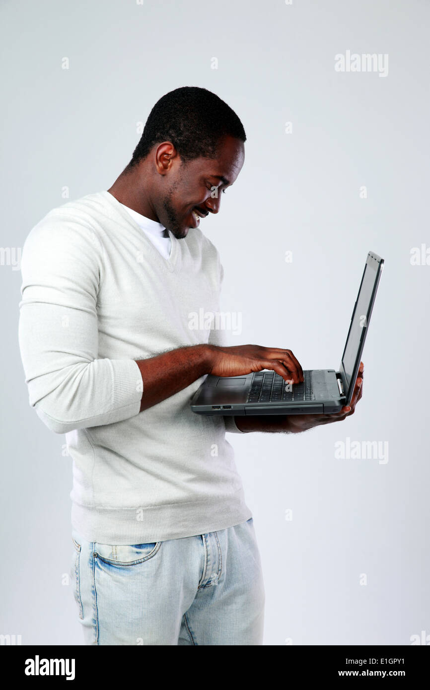 African man using laptop while standing up on gray background Stock Photo