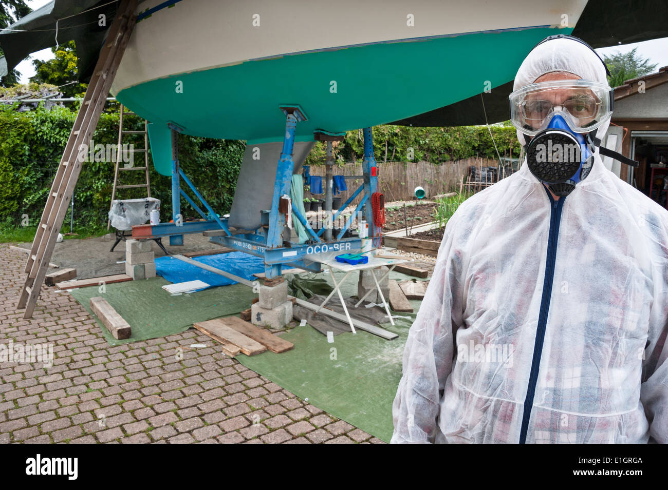 A man, dressed in protective clothing, ready to paint the hull of a