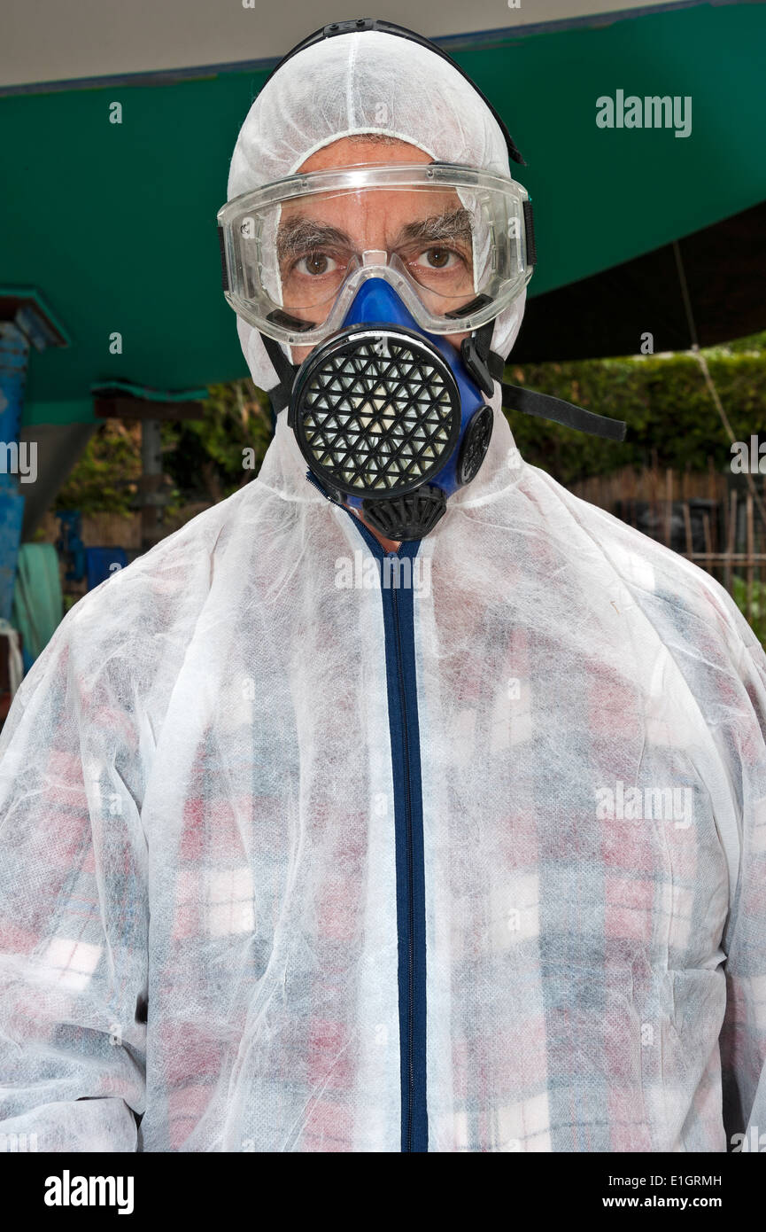 A man, dressed in protective clothing, ready to paint the hull of a yacht (in the background) Stock Photo