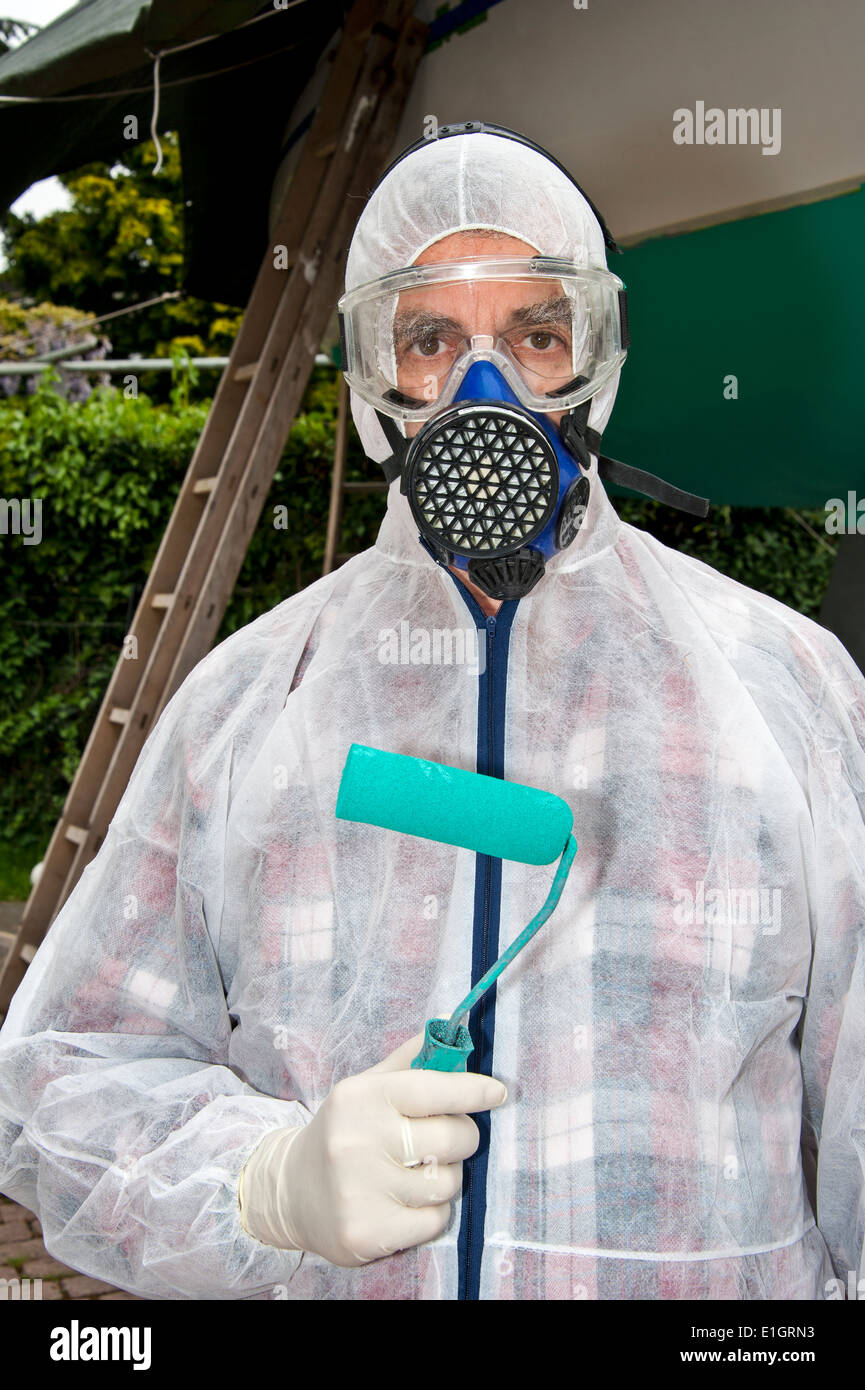 A man, dressed in protective clothing, ready to paint the hull of a yacht (in the background) Stock Photo