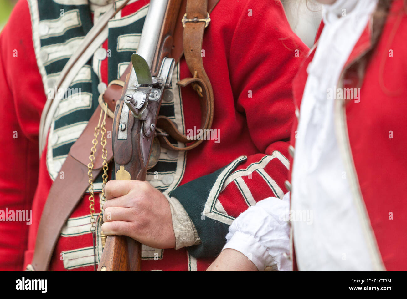 A soldier dressed in traditional 17th Century English Army Redcoat uniform holding shouldered a flintlock musket. Stock Photo