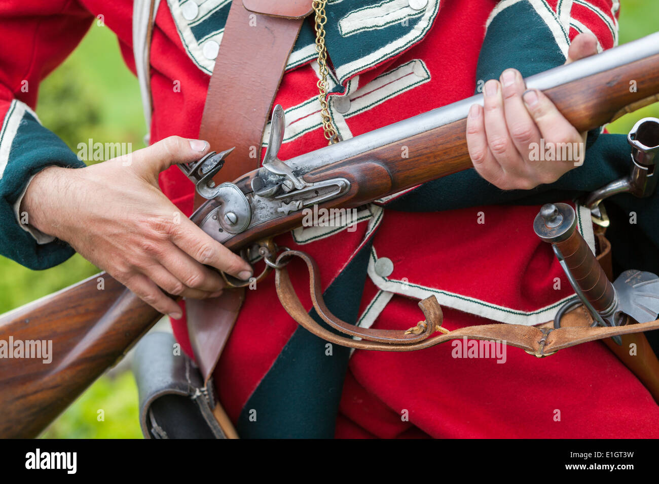 A soldier dressed in traditional 17th Century English Army Redcoat uniform loading a flintlock musket. Stock Photo