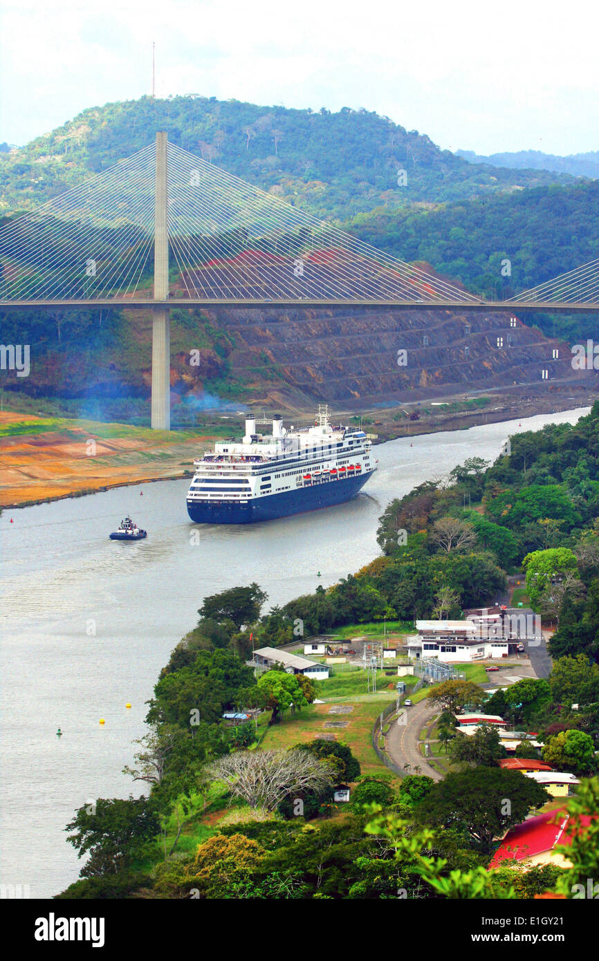 Cruise ship sailing underneath the Centennial Bridge on the Panama Canal. Lush landscape surrounds the canal, Panama. Stock Photo