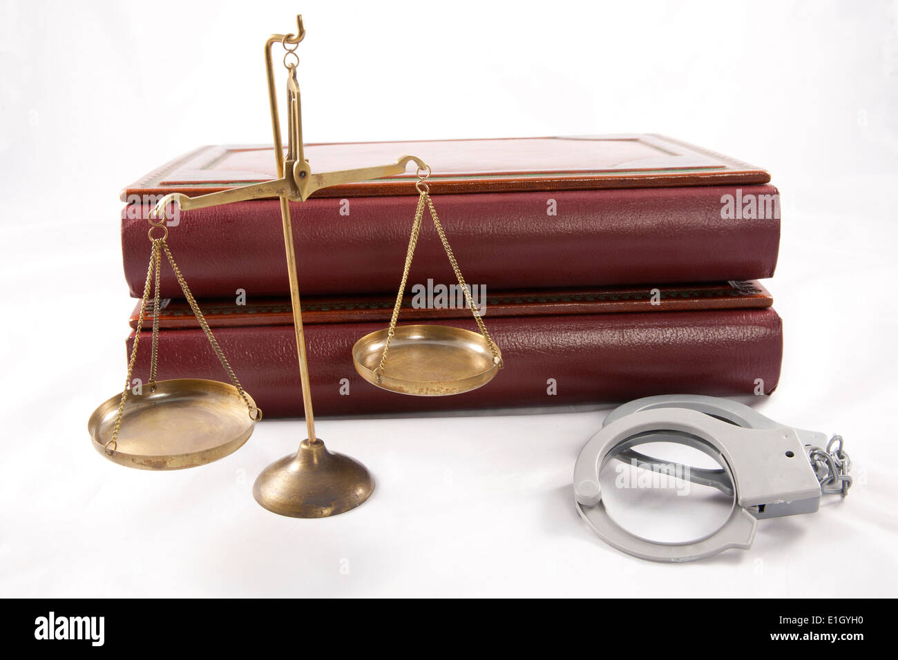 Legal scales, handcuffs and two blank leather bound books on white Stock Photo
