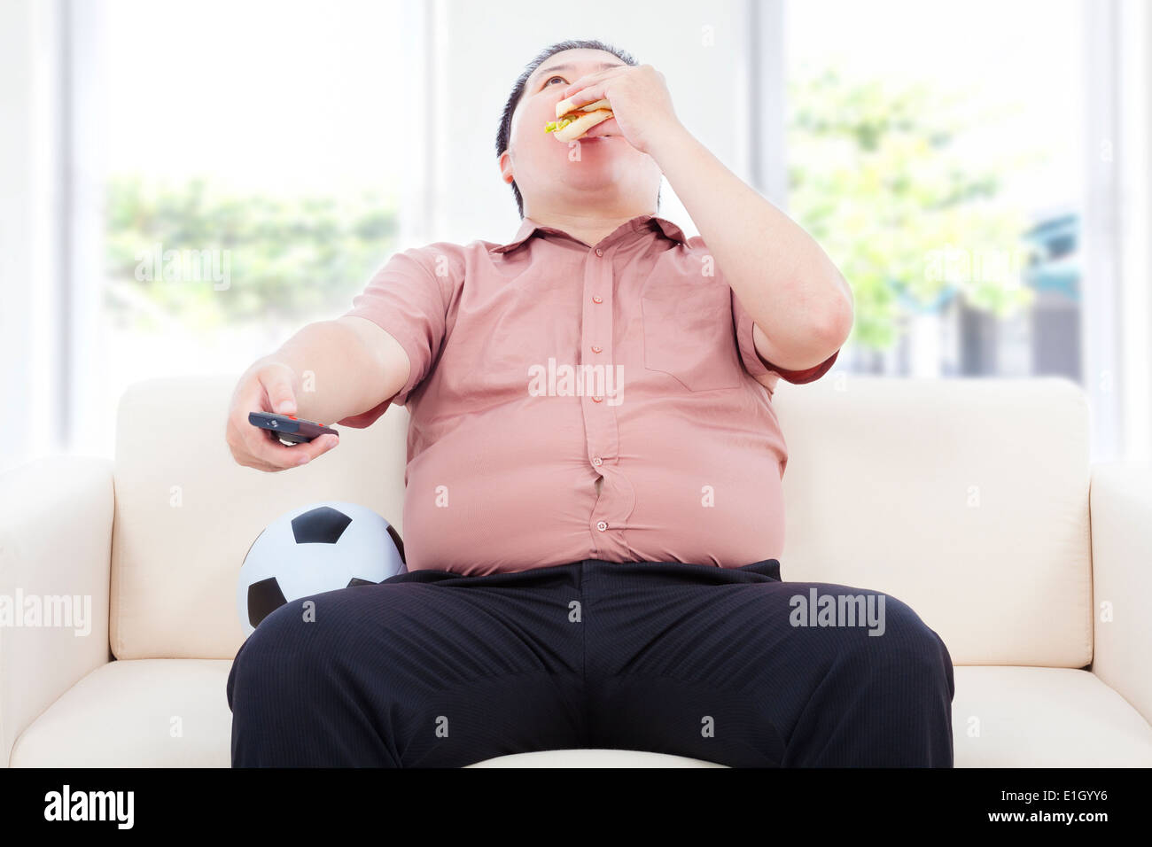 fat business man drinking beer and sitting on sofa to watch TV Stock Photo