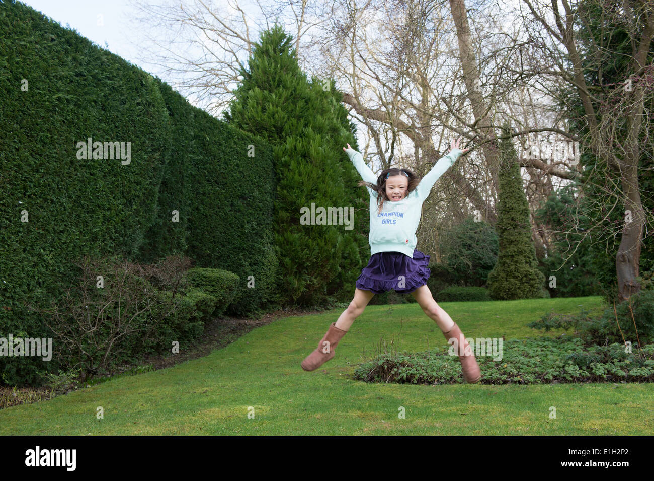 Young girl jumping mid air in garden Stock Photo