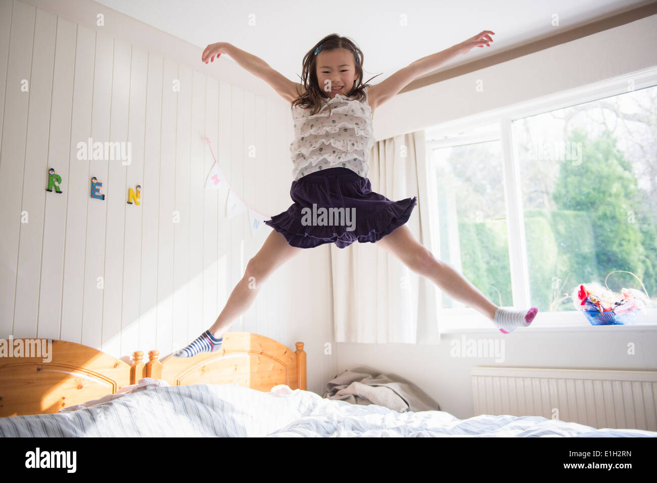 Young girl jumping mid air on bed Stock Photo