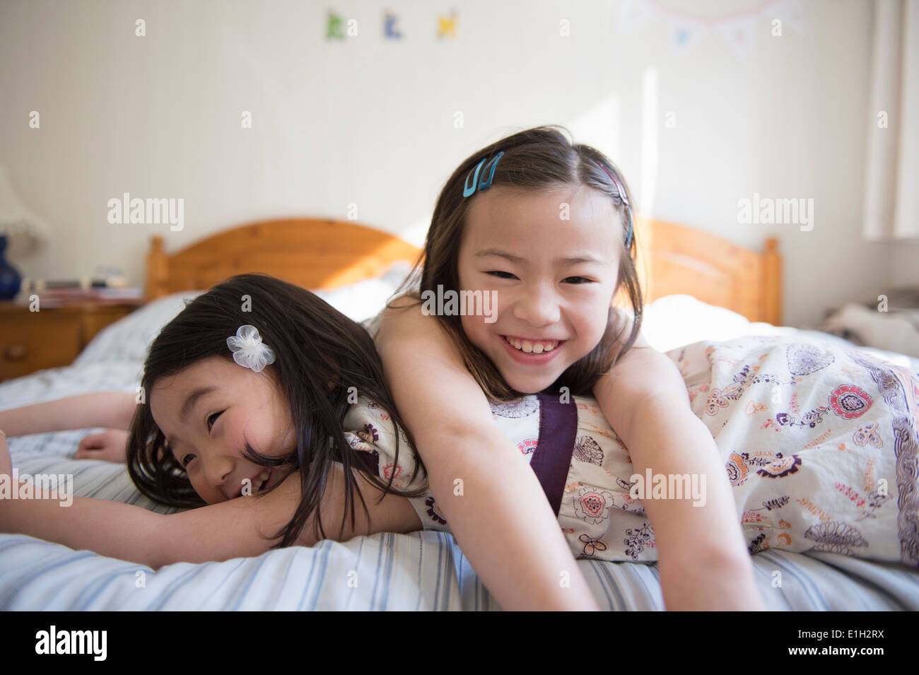 Two young female friends lying on bed Stock Photo