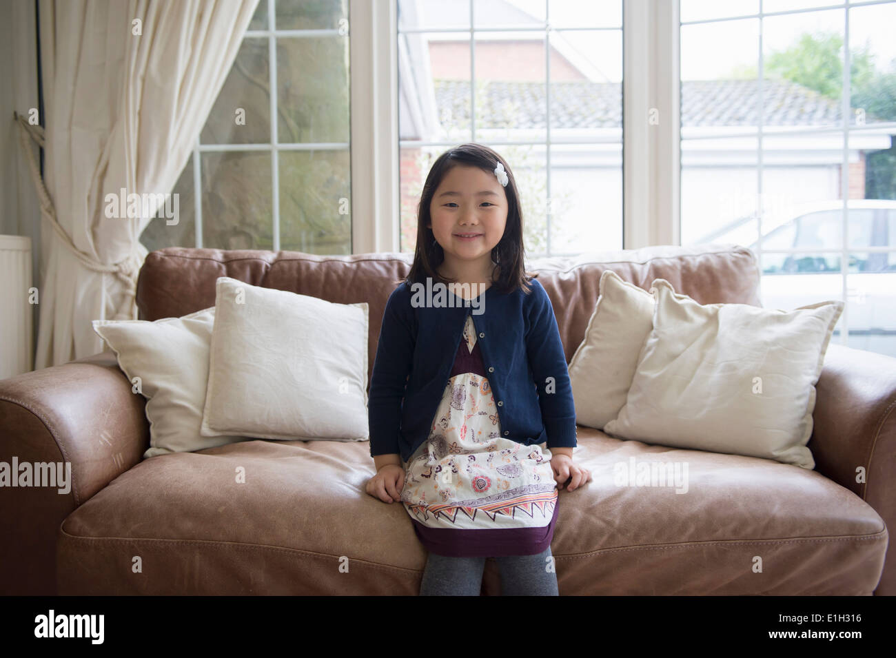 Portrait of young girl sitting on sofa Stock Photo - Alamy