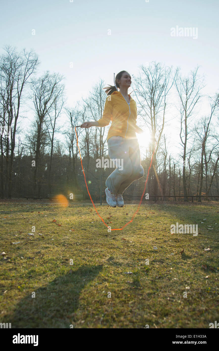 Young woman exercising in field with skipping ropes Stock Photo