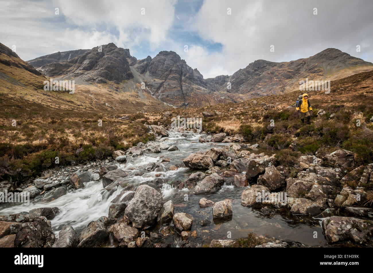 Hiker next to a river with the Black Cuillin's 'Bla Bheinn' Mountain, Isle of Skye, Scotland Stock Photo