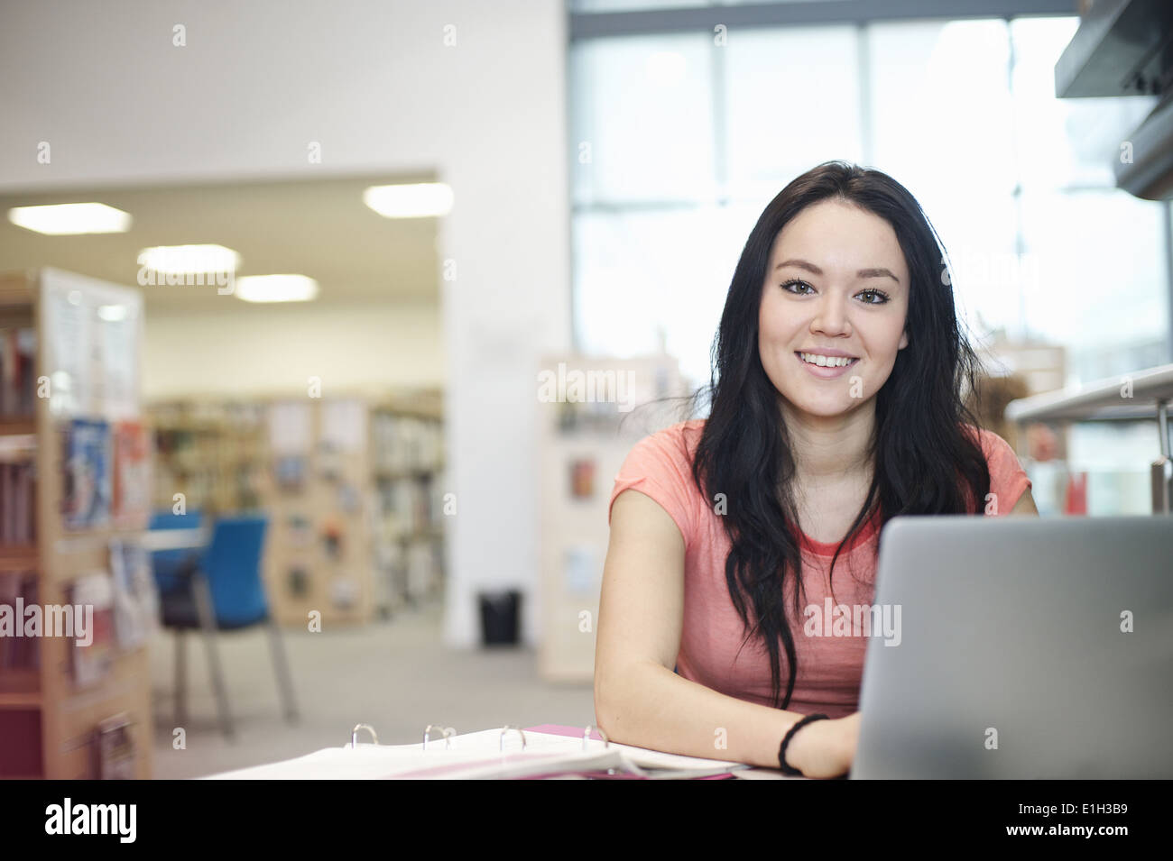 Young woman using laptop in library Stock Photo