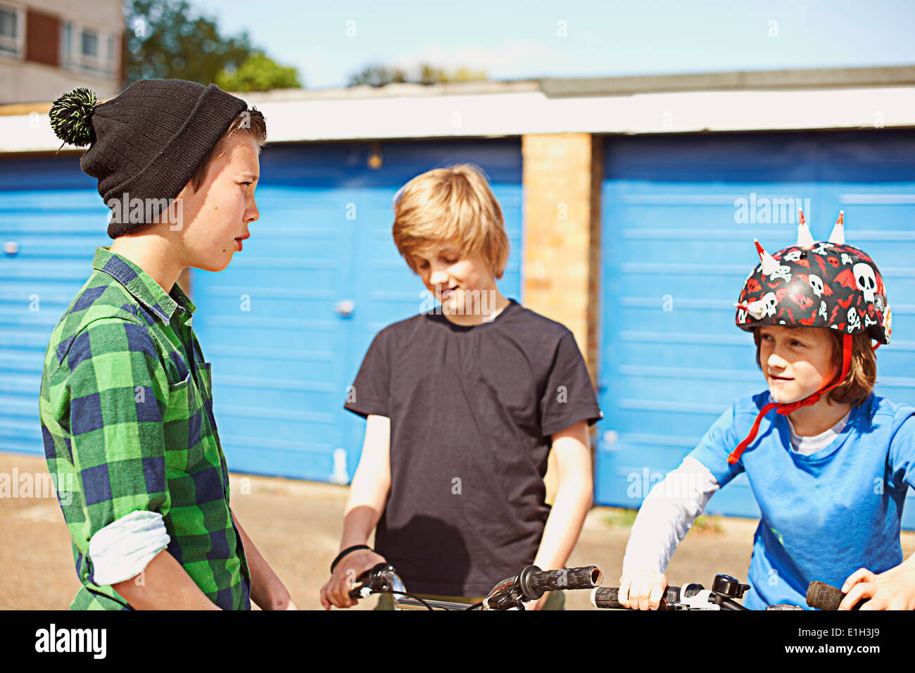 Three boys talking near garages Stock Photo
