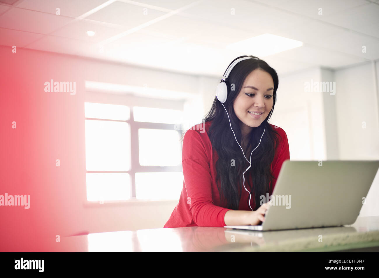Young woman wearing headphones using laptop Stock Photo