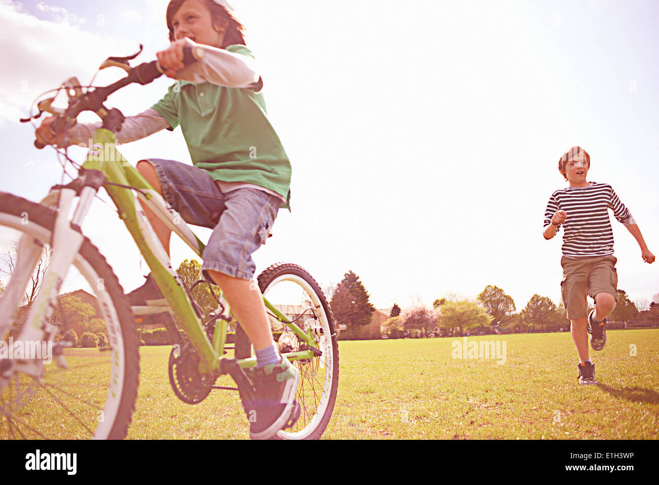 Boys running and cycling on playing field Stock Photo