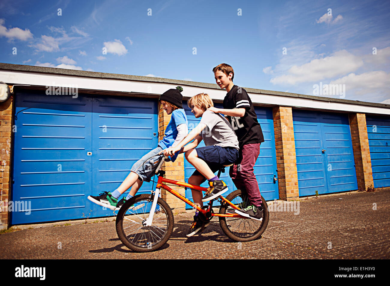 Boy giving two friends a ride on bike Stock Photo