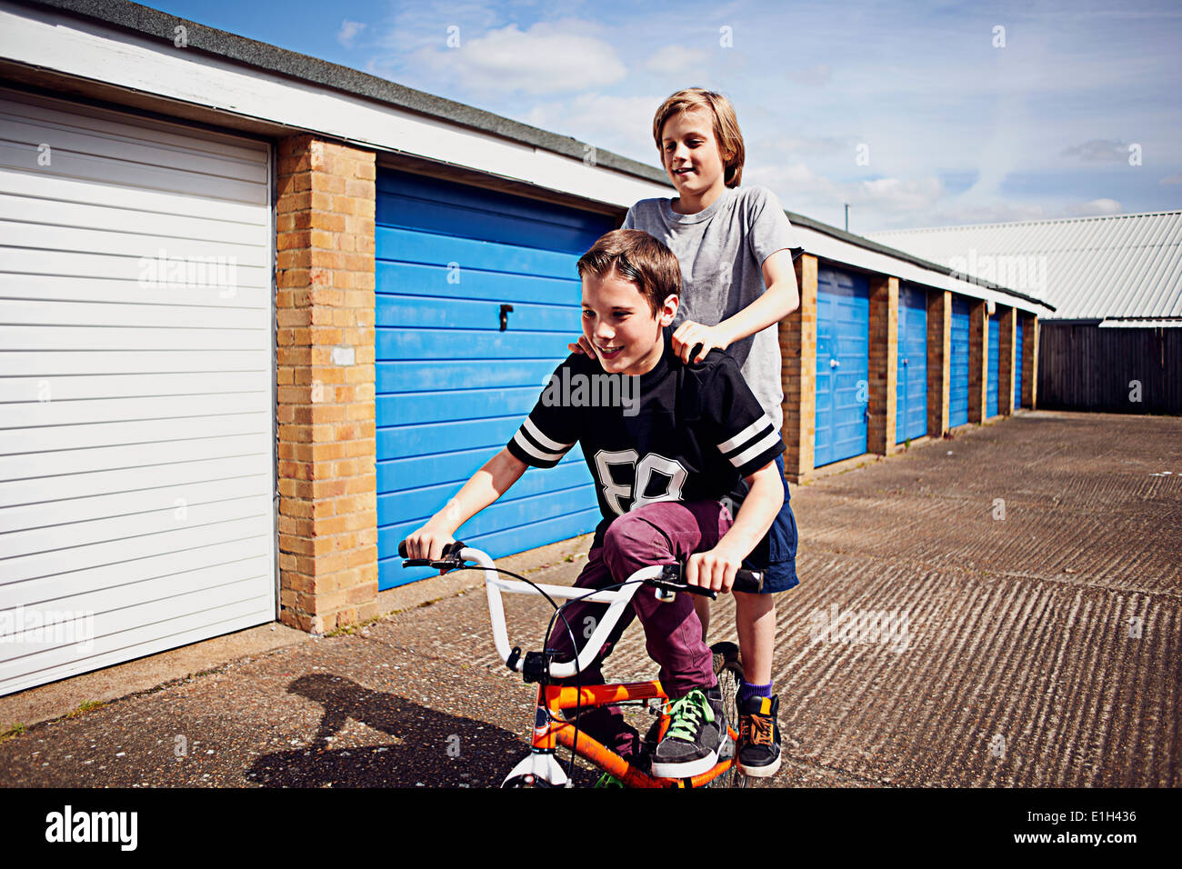 Boys giving friend a ride on bike Stock Photo