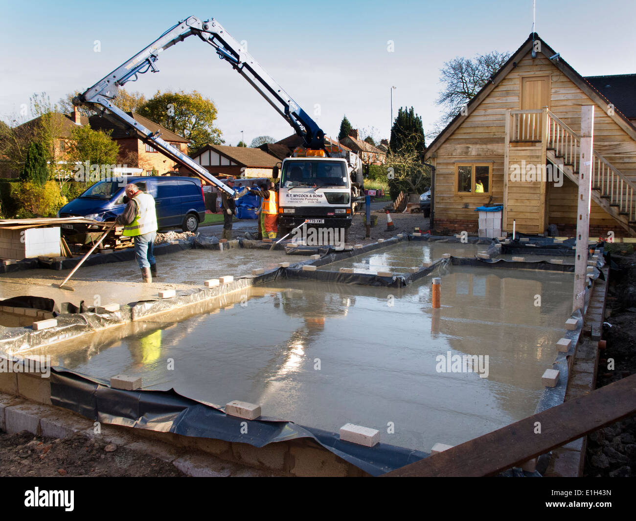 self building house, man tamping freshly poured concrete floor slab