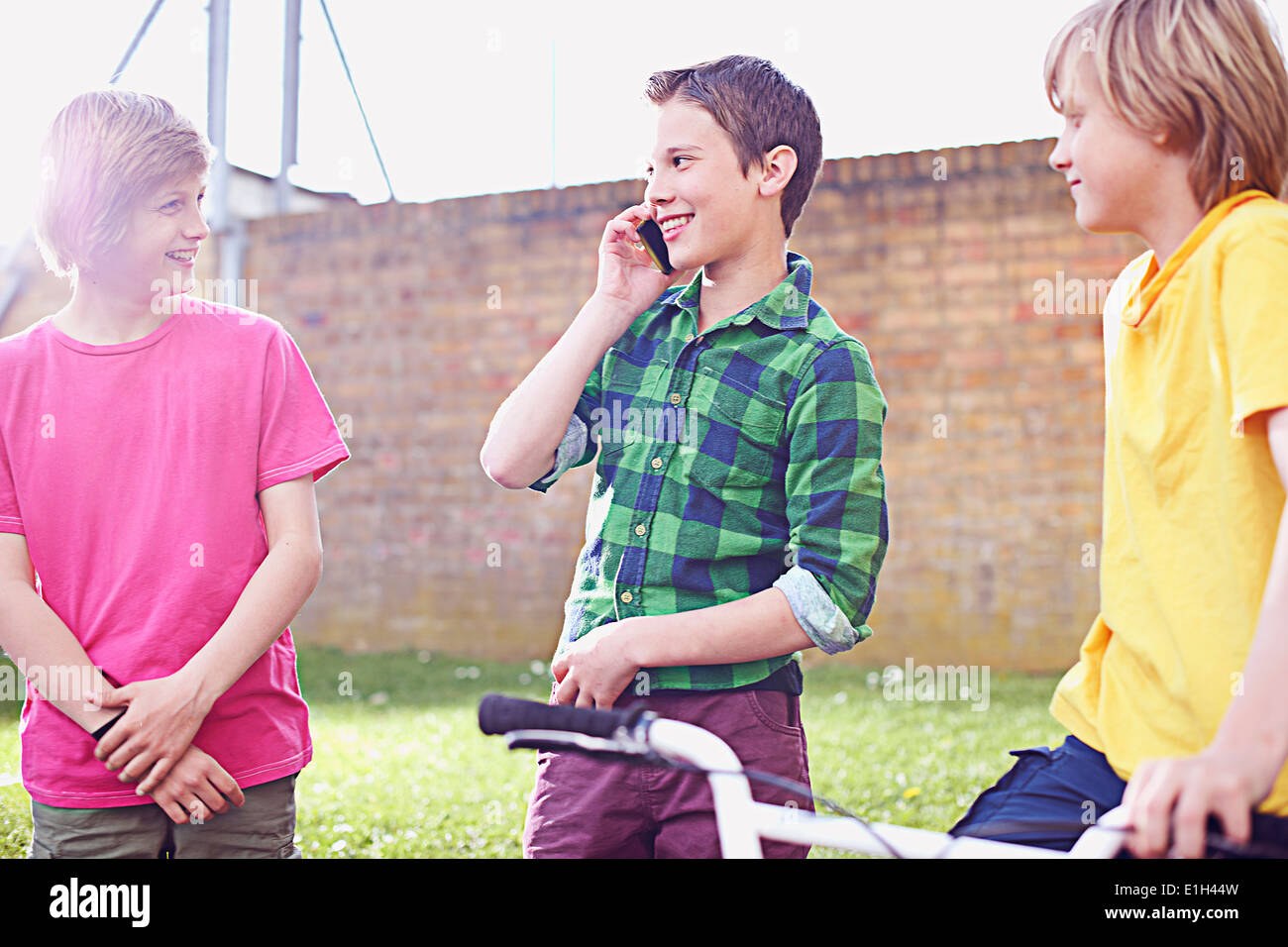Boy using cell phone with two friends Stock Photo