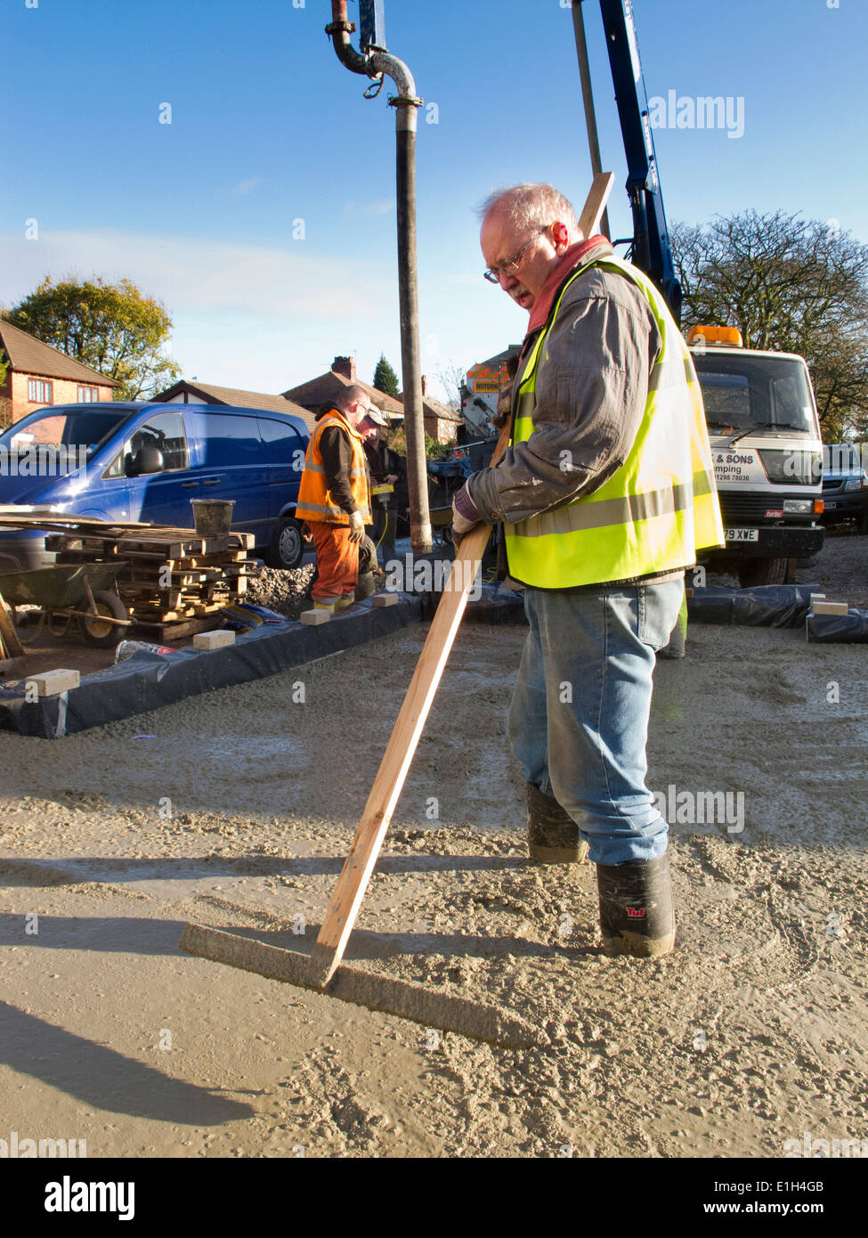 self building house, man tamping freshly poured concrete floor slab