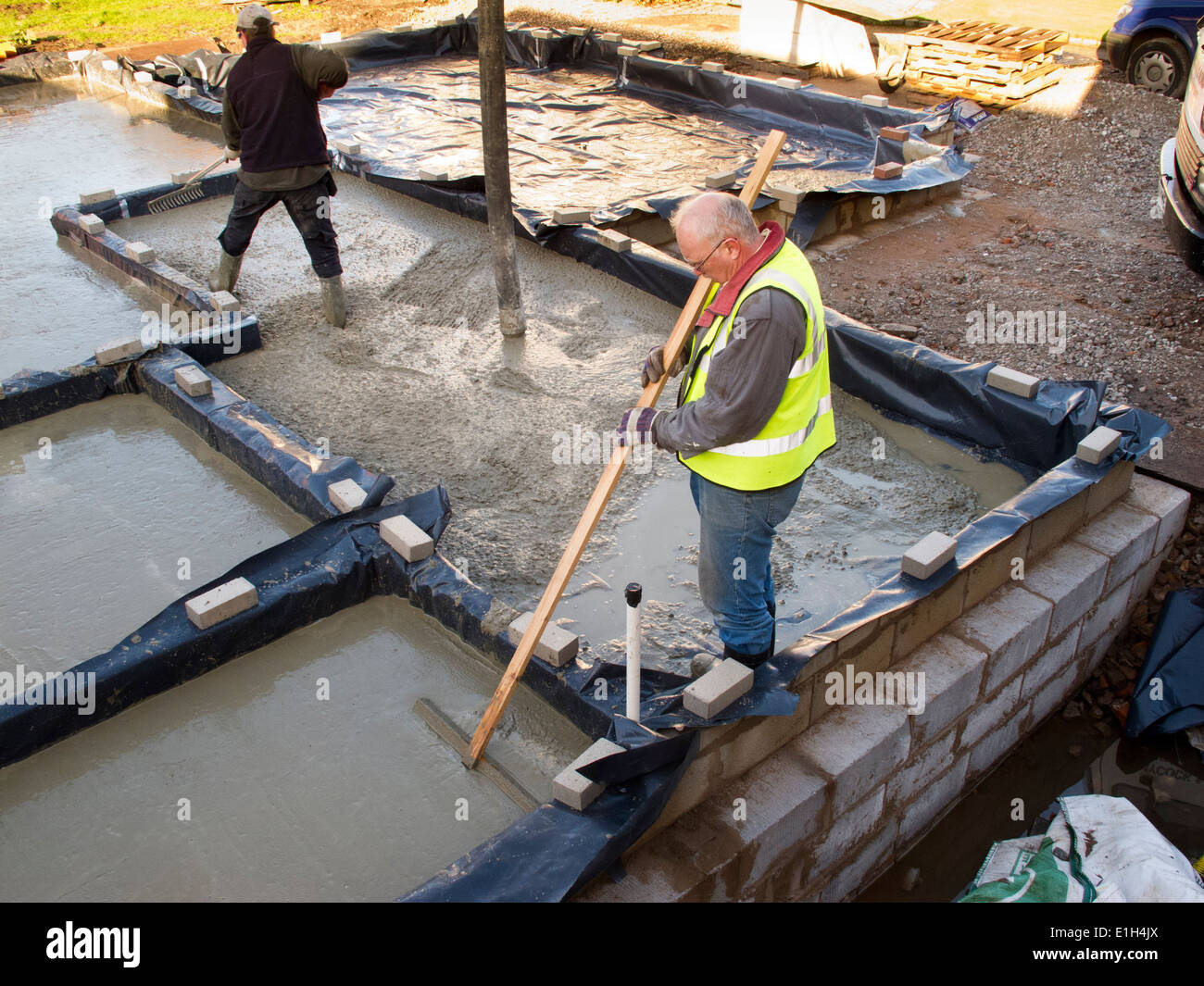self building house, pouring floor slab, man levelling concrete by hand raking Stock Photo Alamy