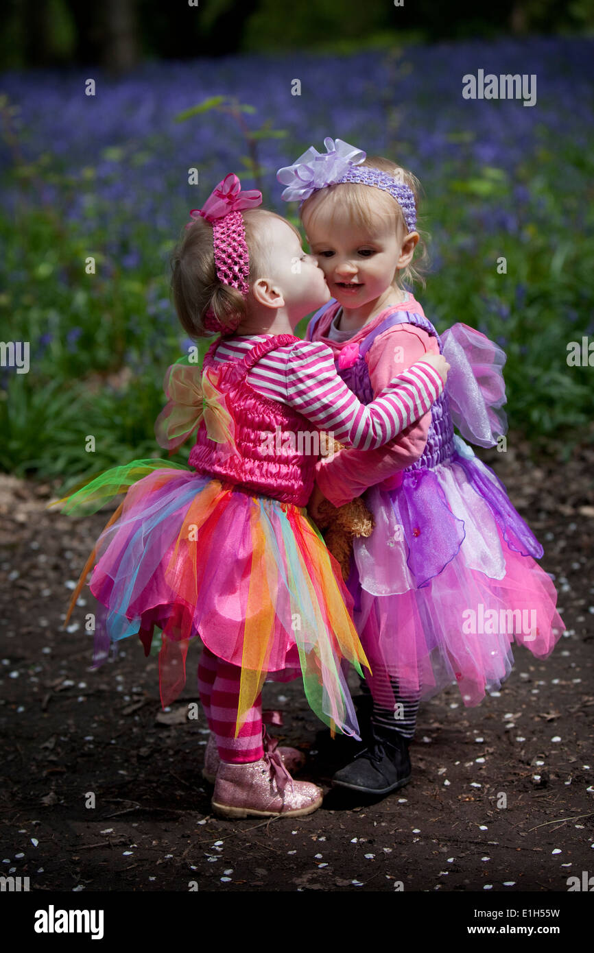 Two little girls in pink fairy dresses playing in an English woodland in Spring. Stock Photo