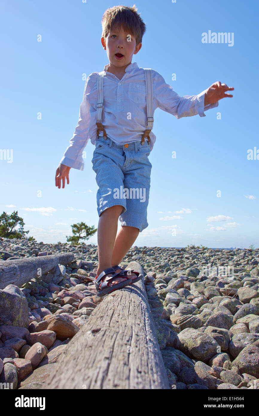 Boy balancing on log on beach Stock Photo