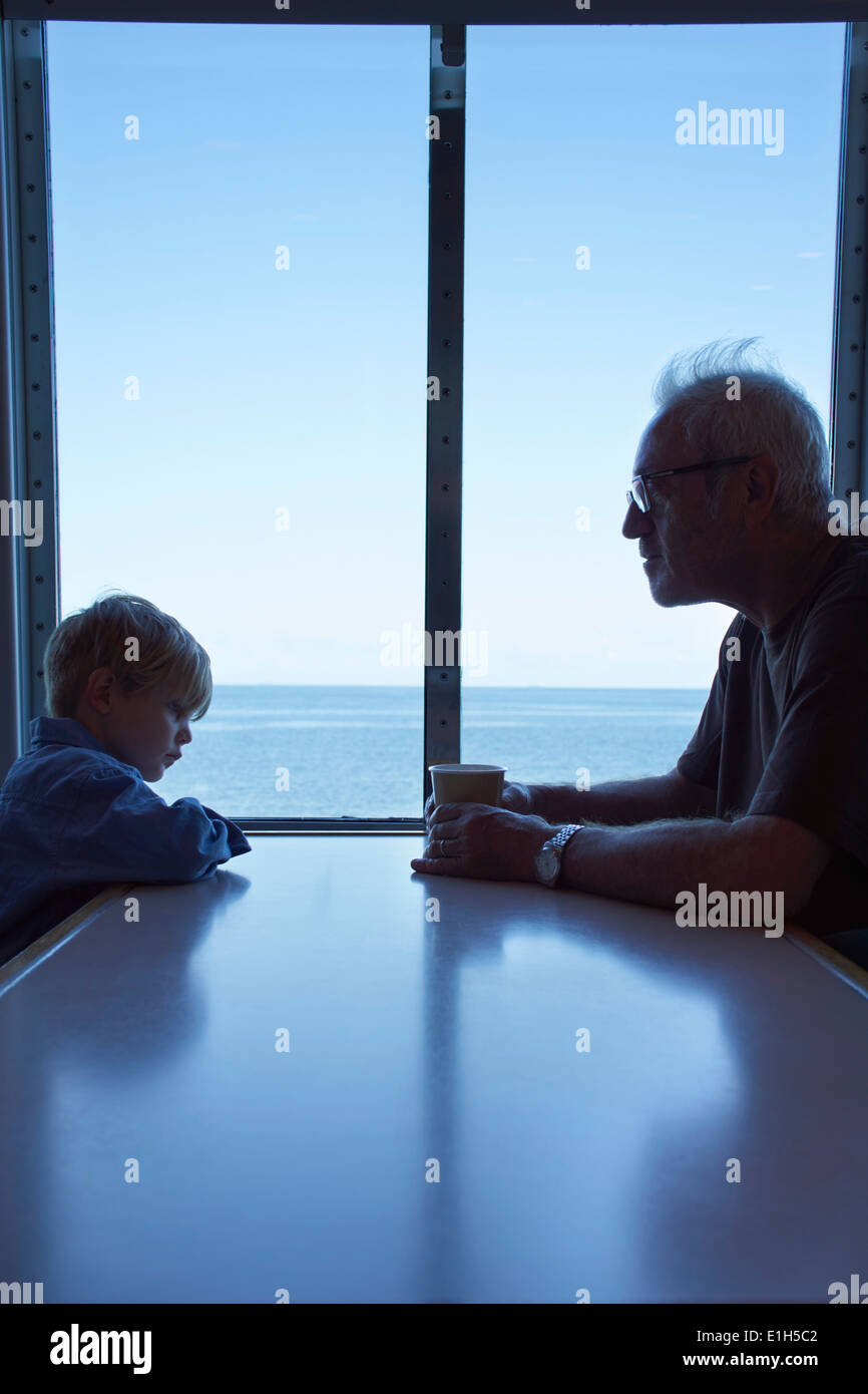 Young boy and father sitting at table on ferry Stock Photo