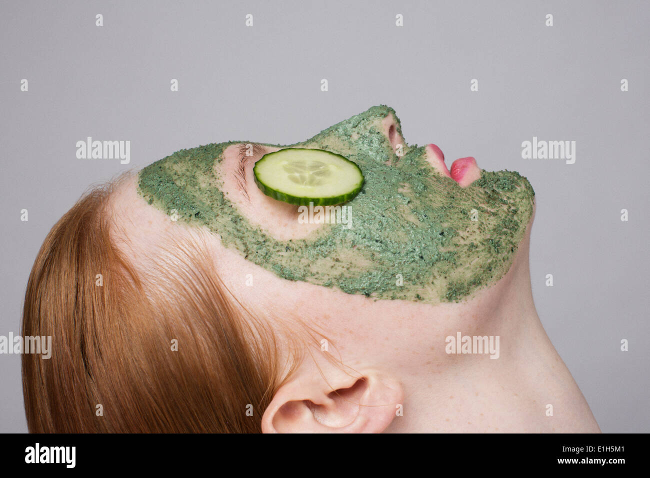 Young woman wearing face mask and cucumber over eyes Stock Photo