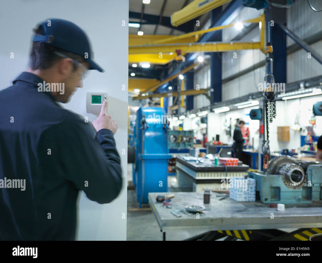 Factory worker adjusting thermostat in factory Stock Photo